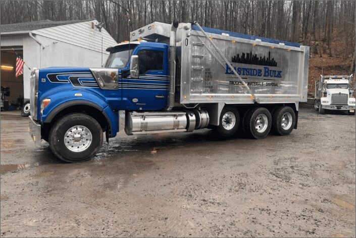 A blue Eastside Bulk tri-axle dump truck in the yard